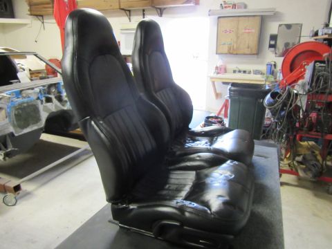 Two black leather bucket seats in a garage setting