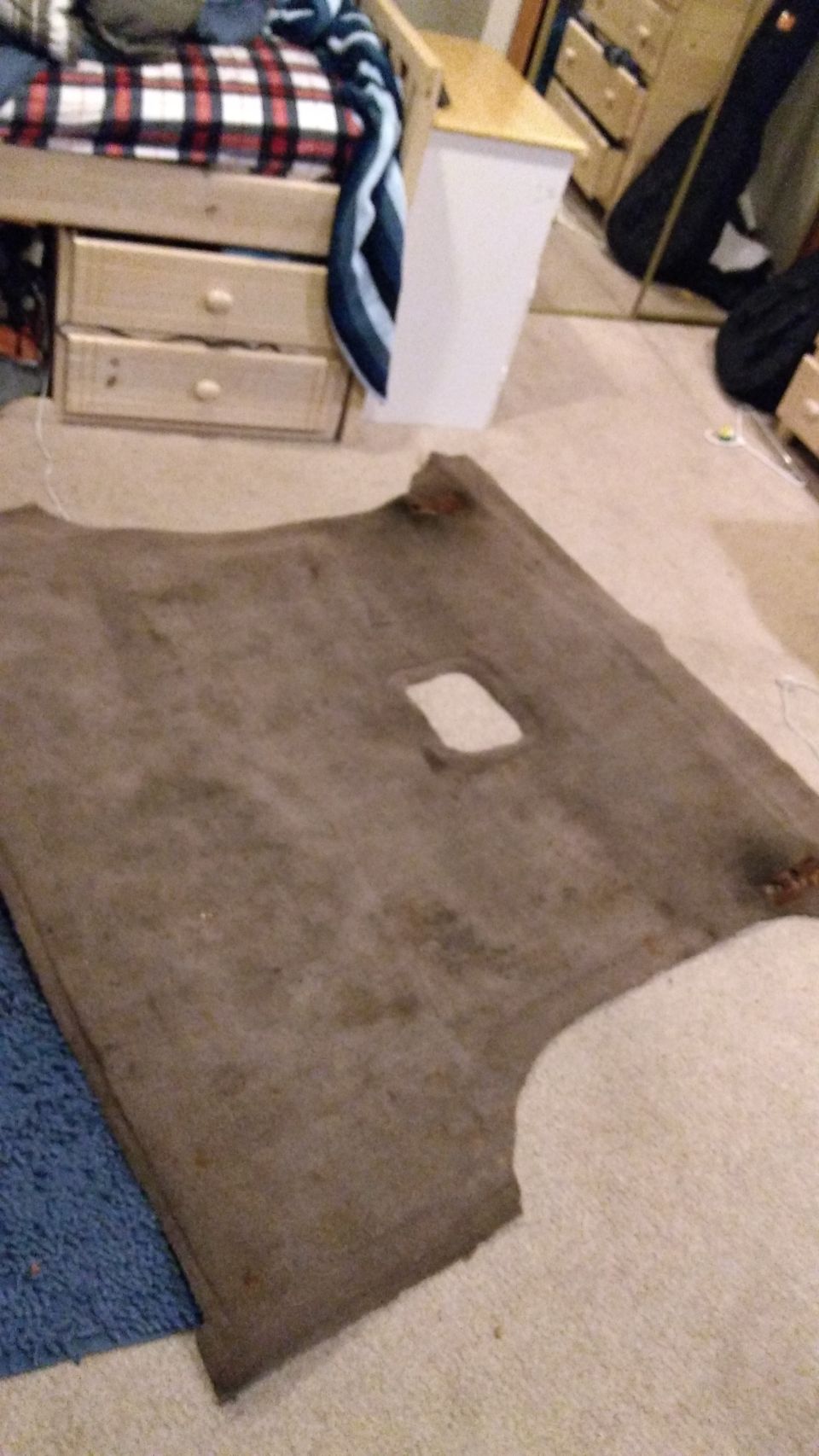 Worn gray headliner board with sunroof opening lying on a bedroom floor