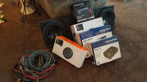 1996 Ford Bronco - Various car audio components are laid out on a carpeted floor, including speakers, amplifiers, and wiring harnesses.