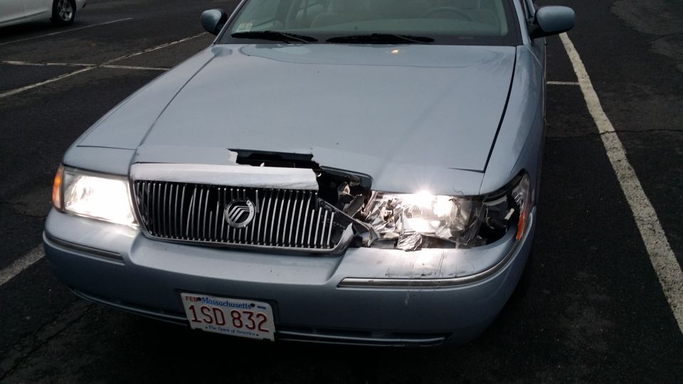 Light blue sedan with damaged front grille and headlight, Massachusetts license plate 1SD 832