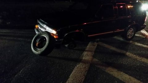 1999 Chevrolet Blazer - A dark 1999 Chevrolet Blazer is shown with a detached tire and missing front wheel.