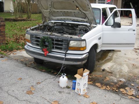 1994 Ford Bronco - A white Ford F-Series truck is parked with its hood open, a wreath on the grille, and tools nearby.