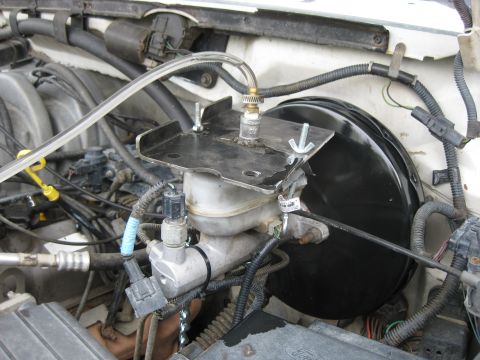 1994 Ford Bronco - Close-up view of the brake master cylinder and booster assembly, showing connected tubing and wiring.