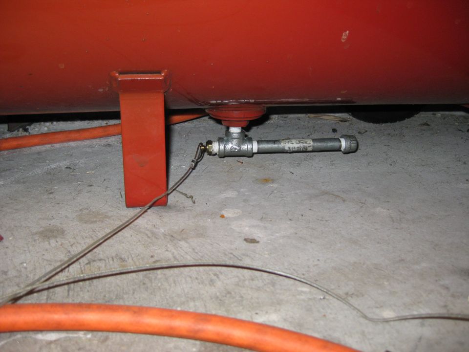 Red air compressor tank bottom with drain valve and orange hose