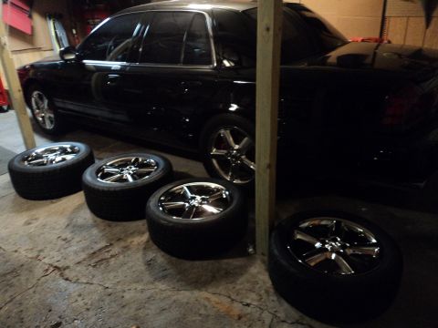 2004 Mercury Grand Marquis - A 2004 Mercury Grand Marquis is parked in a garage with four aftermarket chrome rims laid out beside it.