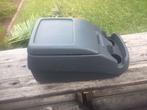 1986 Ford Bronco - Center console part with cup holders and storage compartment, photographed outdoors.