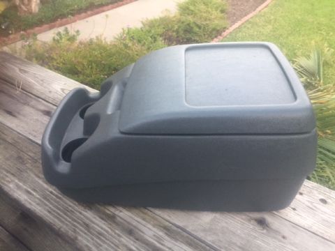 1986 Ford Bronco - This is a vehicle's center console with cup holders, shown outdoors on a wooden surface.