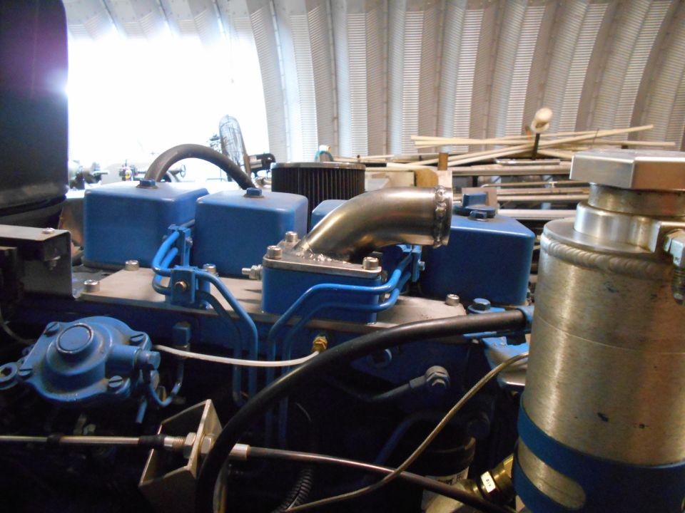 Close-up of blue engine components with a silver intake pipe