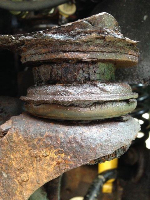 1995 Ford Bronco - Close-up of a severely corroded vehicle suspension part, showing significant wear and tear.