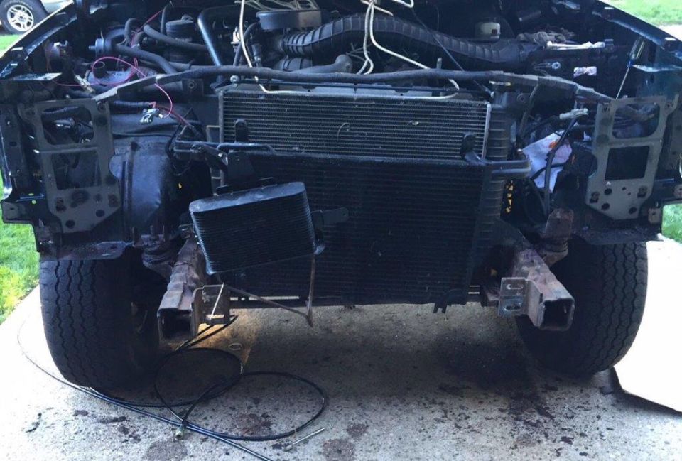 Front end of a disassembled 1990s era SUV, showing radiator, engine components, and exposed frame