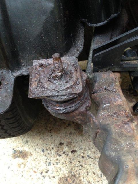 1995 Ford Bronco - Close-up view of a heavily rusted radiator support bracket and mounting bolt.