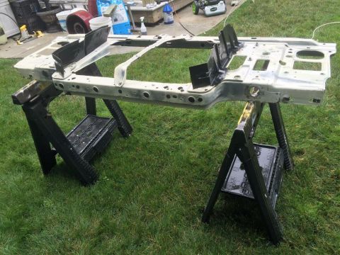 1995 Ford Bronco - Vehicle frame is supported by sawhorses on a grassy lawn.