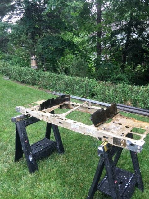1995 Ford Bronco - This radiator support assembly is shown on sawhorses in a grassy yard, with trees and bushes in the background.