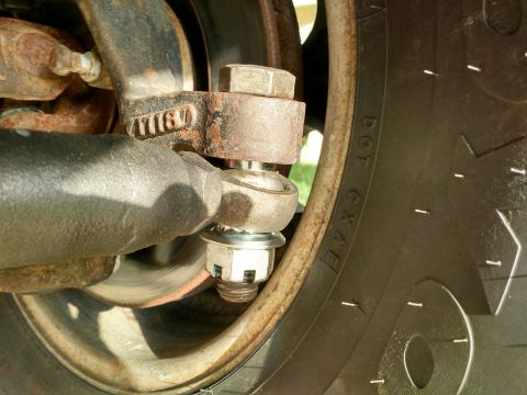 1992 Ford Bronco - A close-up view of a rusty suspension component, likely a ball joint or tie rod end, secured with a castle nut and cotter pin.