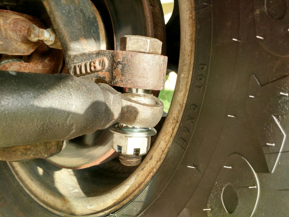 Close-up of a rusty suspension component with a castle nut and cotter pin