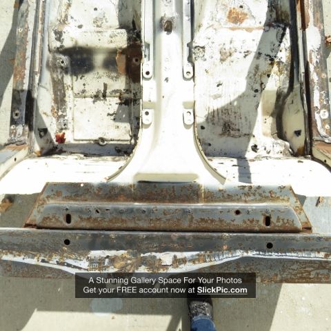 1976 Chevrolet Corvette - The bare frame of a vehicle, showing significant rust and wear, is displayed outdoors under bright sunlight.