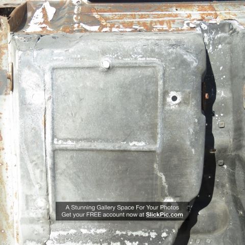 1976 Chevrolet Corvette - The undercarriage of a vehicle shows significant wear and damage, with a metal panel a central raised section.