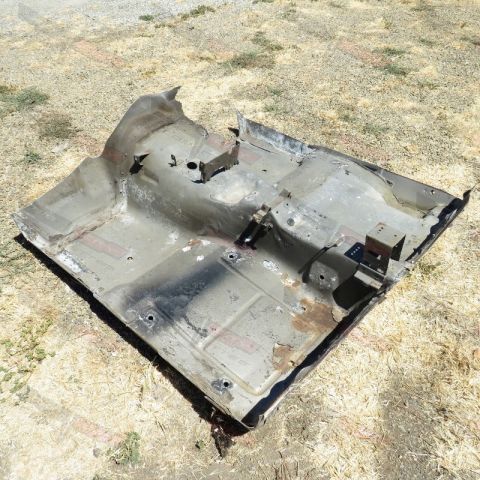 1976 Chevrolet Corvette - This is a damaged and rusted floor pan, likely from a Corvette, lying on the ground.
