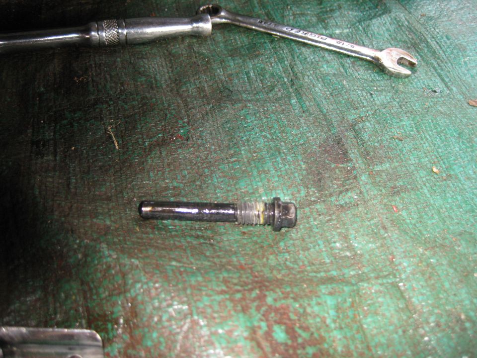 Bolt with washers on a green surface with tools.