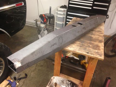 1979 Ford Bronco - A custom-fabricated steel bumper is shown on a workbench, likely for a 1979 Ford Bronco. The bumper is a long, angular, rectangular prism w…