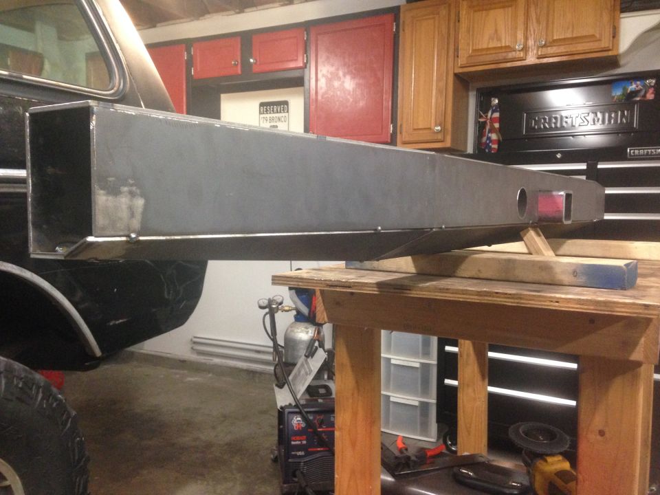 Custom steel bumper mounted to the rear of a vehicle, supported by wooden blocks on a workbench.