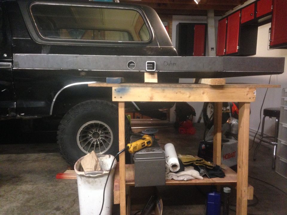 Black Ford Bronco with a metal panel being worked on in a garage.