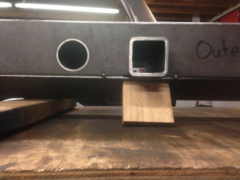 1979 Ford Bronco - A close-up, low-angle view of a fabricated steel frame, possibly part of a vehicle chassis, showing a circular cutout and a square opening.…