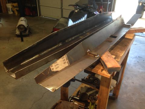 1979 Ford Bronco - Two long, fabricated metal channels are shown in a garage setting. One channel is resting on a workbench, while the other is on the floor.
