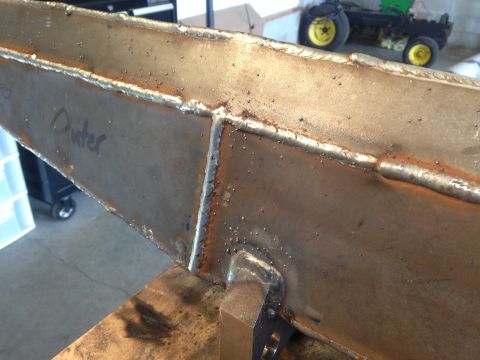 1979 Ford Bronco - A close-up view shows a metal beam with visible welds and some handwritten text that appears to read "Dunter". In the background, a small y…