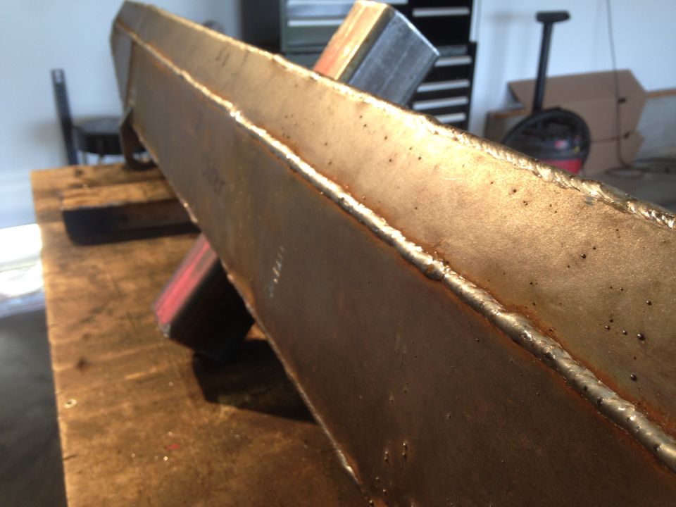 Welded metal beam with rust and weld lines.