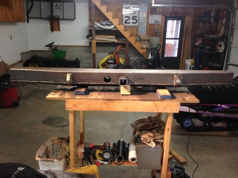 1979 Ford Bronco - A long, heavy metal beam is resting on a wooden table in a garage. The beam has some text written on it that says "Outer".
