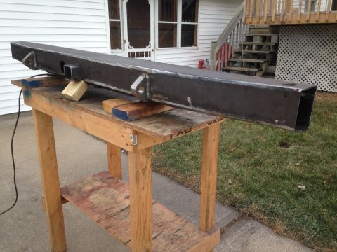 1979 Ford Bronco - A fabricated steel bumper is resting on a wooden workbench outside a house. The bumper has two mounting points on the left and a square rec…