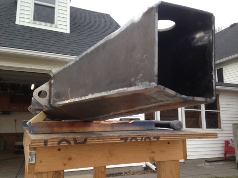 1979 Ford Bronco - A large, fabricated steel rectangular tube with a hole cut into one side is resting on a wooden workbench. The tube appears to be a custom…