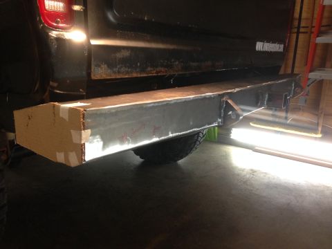 1979 Ford Bronco - A custom fabricated steel bumper is attached to the rear of a dark-colored vehicle, likely a truck or SUV. The bumper features a square tub…