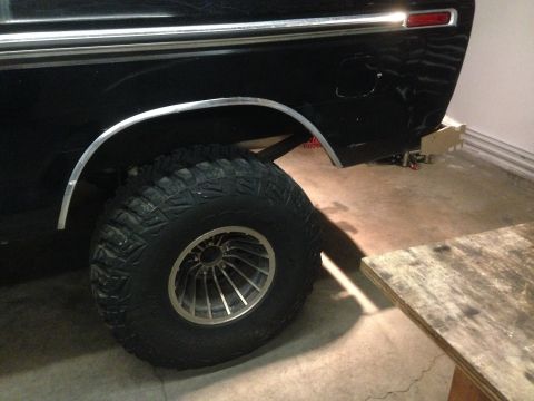 1979 Ford Bronco - The rear passenger side of a black Ford Bronco is shown, featuring a large off-road tire with a chrome and silver multi-spoke rim. The vehi…