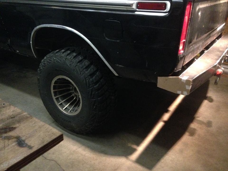 Rear passenger side of a black pickup truck with off-road tire and custom bumper.
