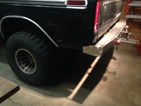 1979 Ford Bronco - The rear driver's side of a black pickup truck is shown, featuring a large off-road tire and a custom metal bumper that is partially covere…