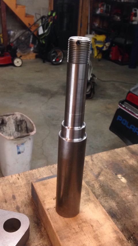 1979 Ford Bronco - A metal shaft with threaded ends is shown resting on a wooden block. The shaft has several stepped diameters and a small hole drilled into…