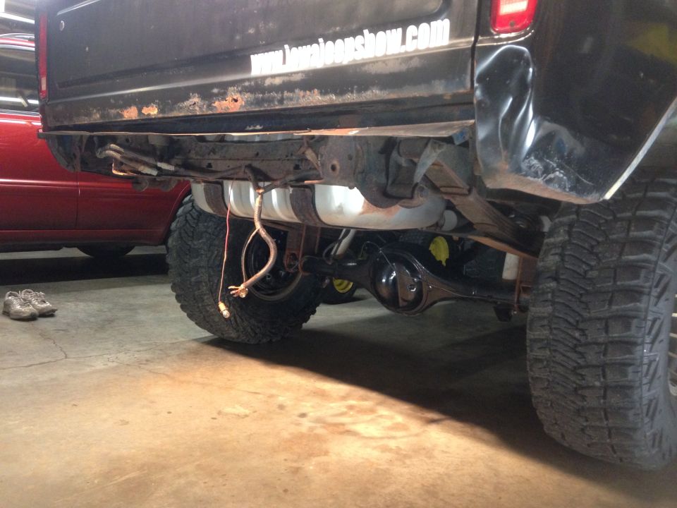 Rear underside of a black pickup truck with fuel tank and wiring.