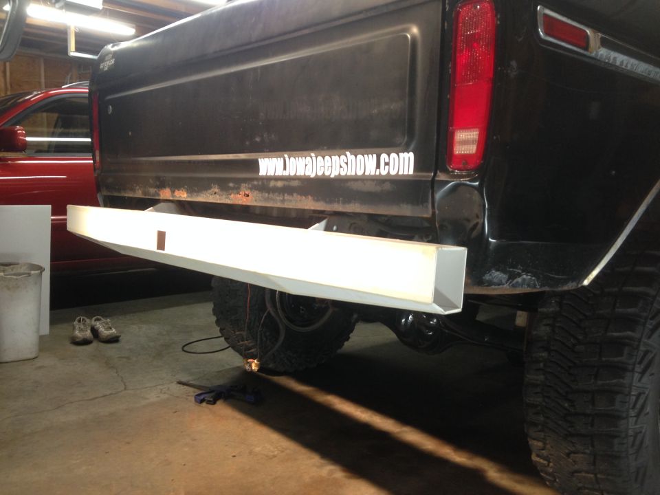 Rear view of a black Ford pickup truck with a white aftermarket bumper and a website sticker on the tailgate.
