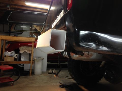 1979 Ford Bronco - The rear driver's side of a black vehicle, likely a truck or SUV, is shown with a large, white, custom exhaust extension attached. The vehi…