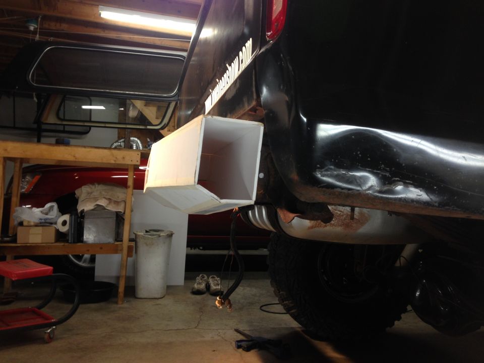 Black vehicle with custom exhaust extension in a garage