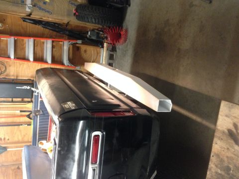 1979 Ford Bronco - The rear of a black vehicle, likely a 1979 Ford Bronco, is shown with a silver aluminum extrusion resting on its trunk lid. A red ladder an…