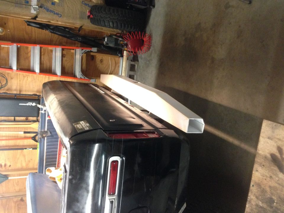 Black vehicle trunk with a silver extrusion on top, garage setting.