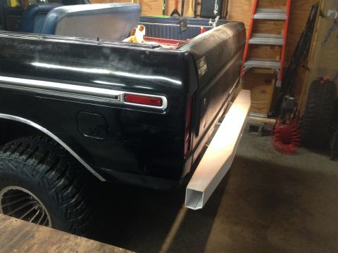 1979 Ford Bronco - The rear driver's side of a black 1979 Ford Bronco is shown in a garage setting. A custom-built square tube bumper is attached to the rear.