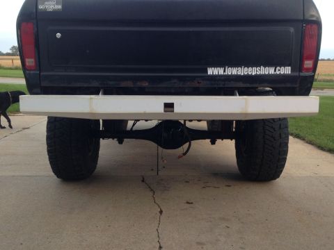 1979 Ford Bronco - The rear view of a black Ford Bronco with a custom white bumper and large off-road tires. A sticker on the tailgate reads "www.iowajeepshow…
