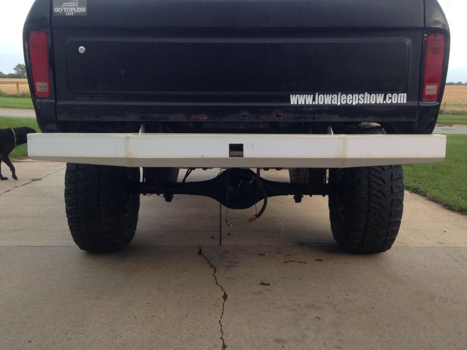 Rear view of a black Ford Bronco with a white custom bumper and large off-road tires.