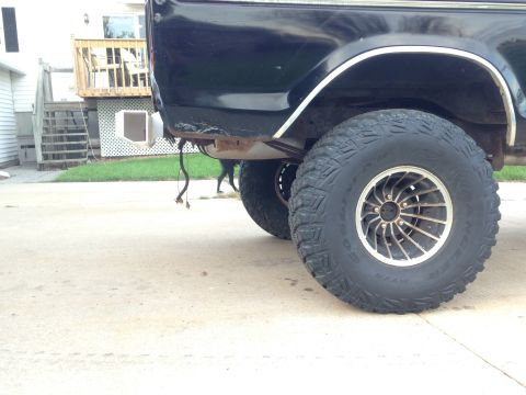 1979 Ford Bronco - Close-up view of the rear wheel and fender of a black SUV, custom rims and large tires.