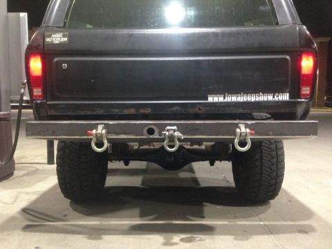 1979 Ford Bronco - The rear of a dark-colored SUV is shown, a custom metal bumper with multiple tow hooks.