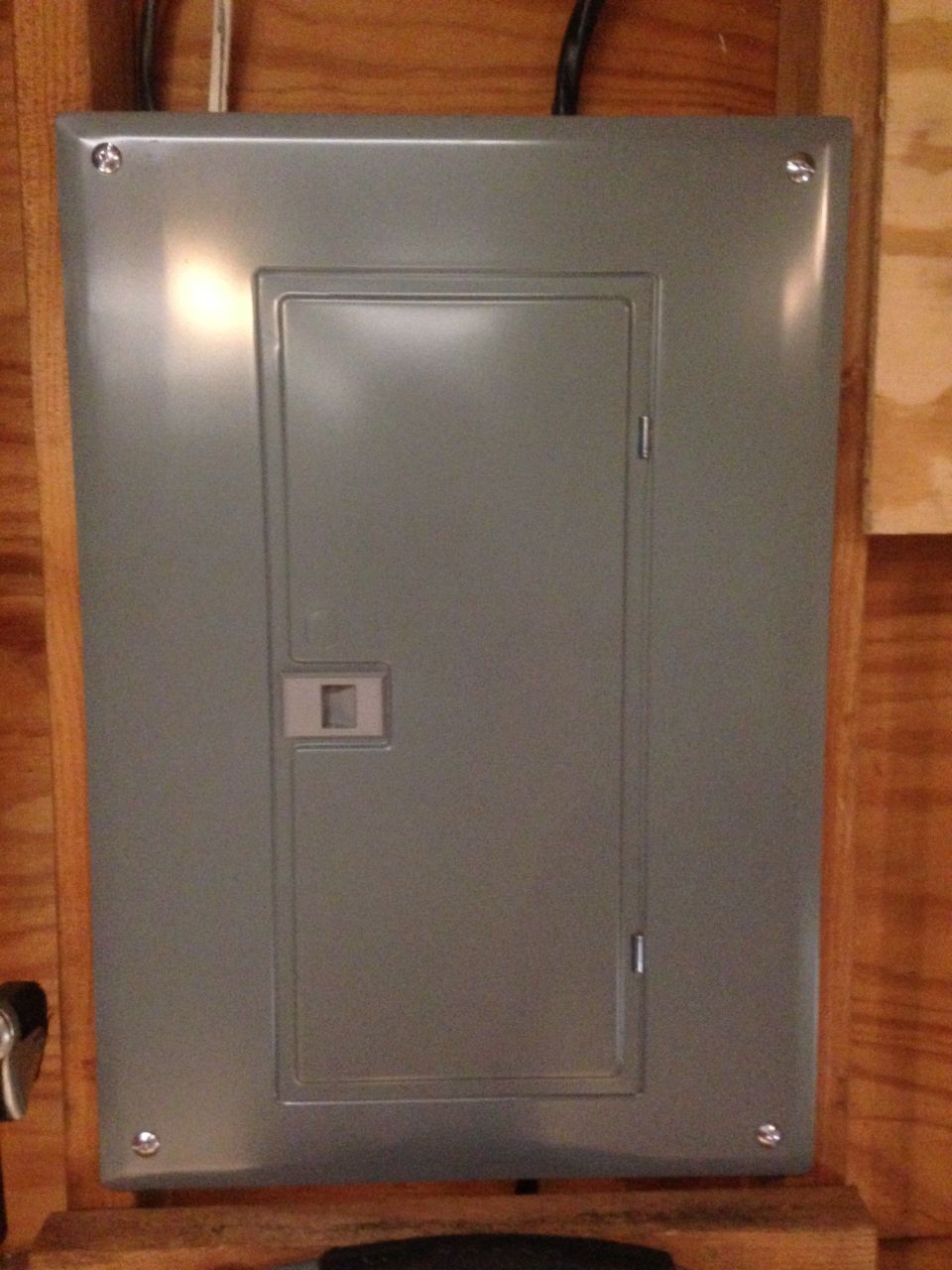 Gray metal electrical panel mounted on wooden wall